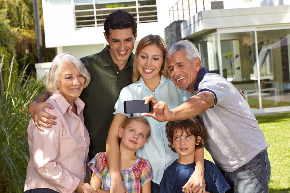 Selfie of family in three generations with children in summer in front of a house