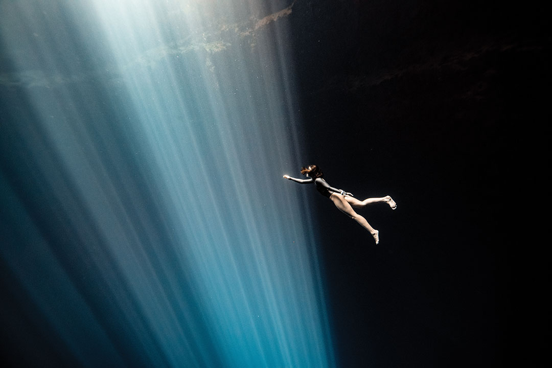 Sofia Gomez Uribe diving underwater with light