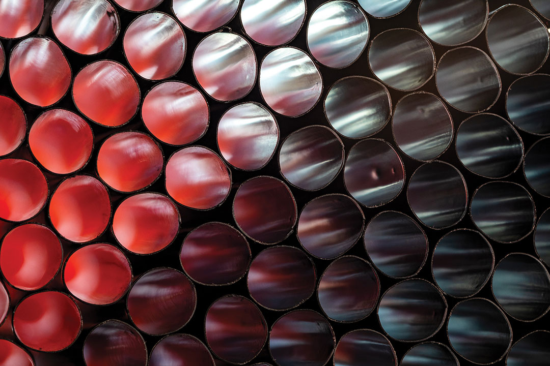 Many black plastic straws with red and orange light shining from the back - close-up view