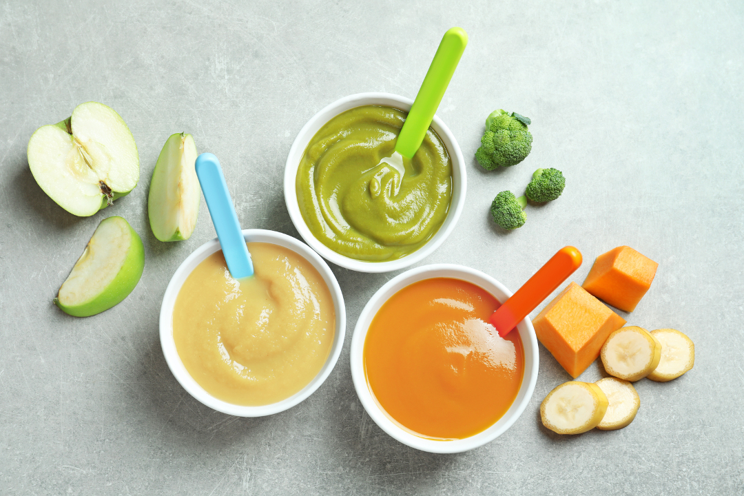 bowls with baby's food on grey background