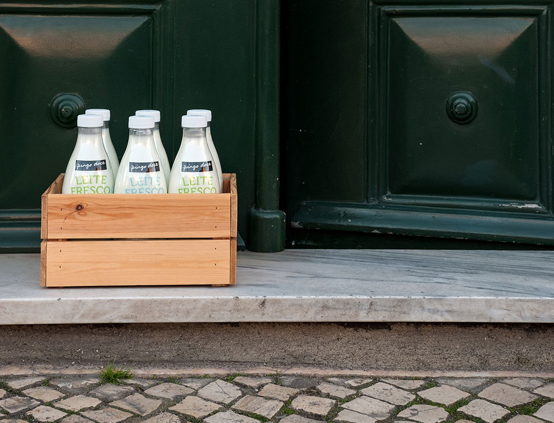 Basket full of fresh milk bottles, in front of a door.