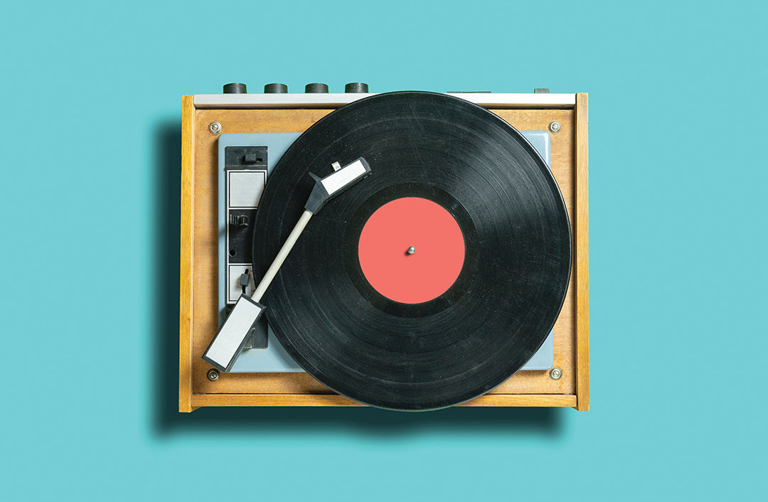 vintage vinyl disc record with coral label on dj turntable on blue background. retro sound technology to play music