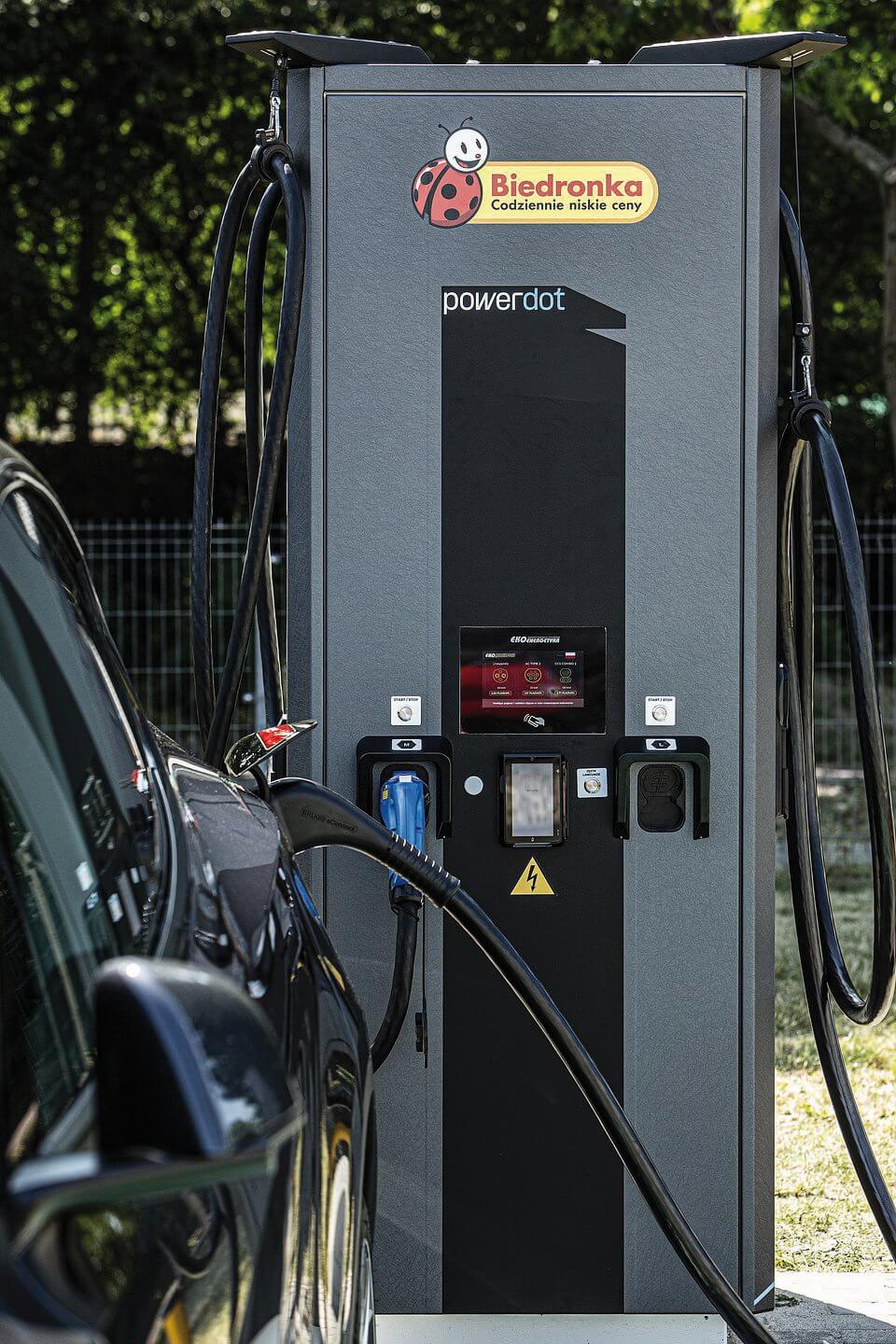  image of a vehicle eletric charger, with Biedronka's logo, on na outside parking station.