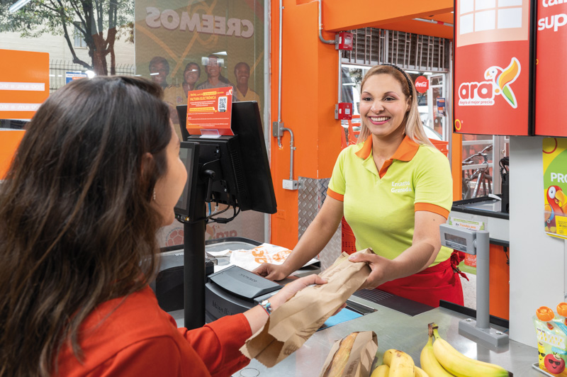 photo of a woman working on a supermarket checkout, smiling