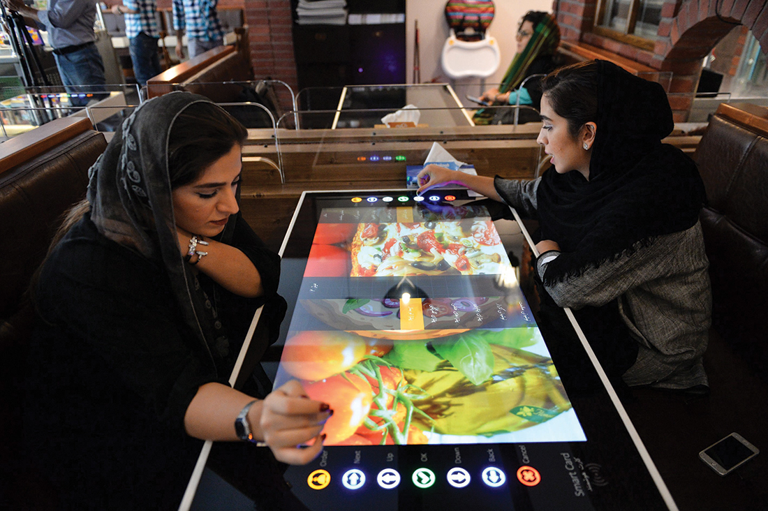 Women select their food served by robot waiter, which moves on rail system placed between tables, at the first robotic restaurant 'RoboChef' in Tehran, Iran on October 11, 2017.