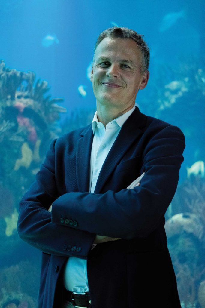 Photography of João Falcato in front of big aquarium of Oceanário