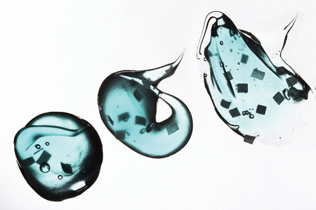 Smear paint of cosmetic products on a white background, micro beads particles in blue transparent toothpaste