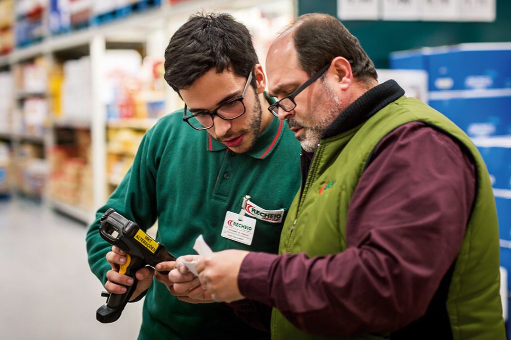 Joaquim Henriques helping a trainee. Placing price tags on products is one the tasks.