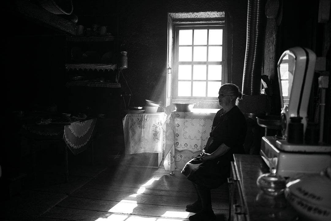 Black and white photography of an old woman in her house