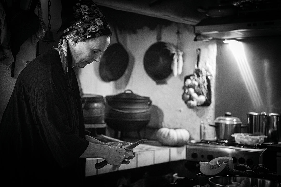 Black and white photography of Eugénia, in her kitchen preparing food