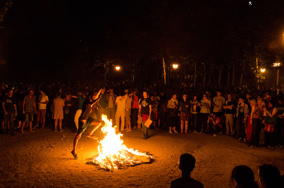 MADRID, SPAIN - 23 June 2013: A man jumping through the fire of a bonfire during Saint John's Eve in Madrid surrounded by hundreds of people.