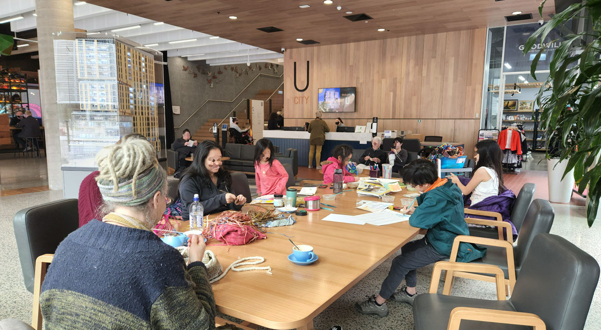 U City lobby featuring the concierge (background) and lounge/dining area hosting a Friday morning art group session (foreground)