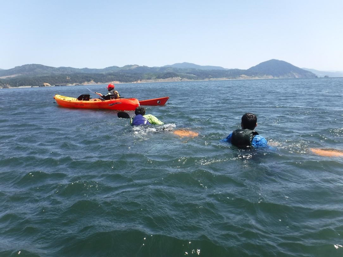 Students learning kayak recovery techniques in the ocean