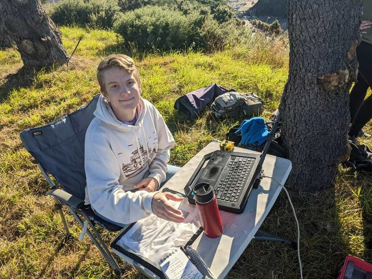 Student operating laptop on cliff site