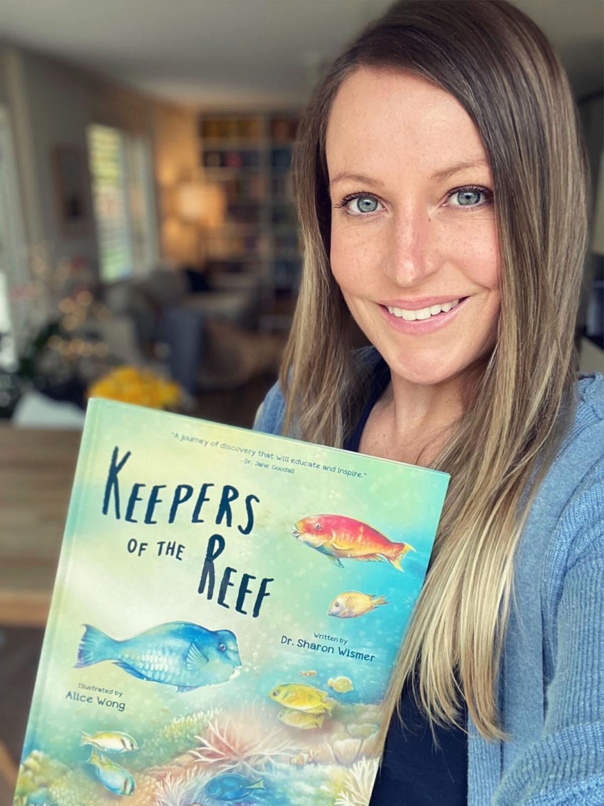 Dr. Sharon Wismer holds a copy of her book, Keepers of the Reef