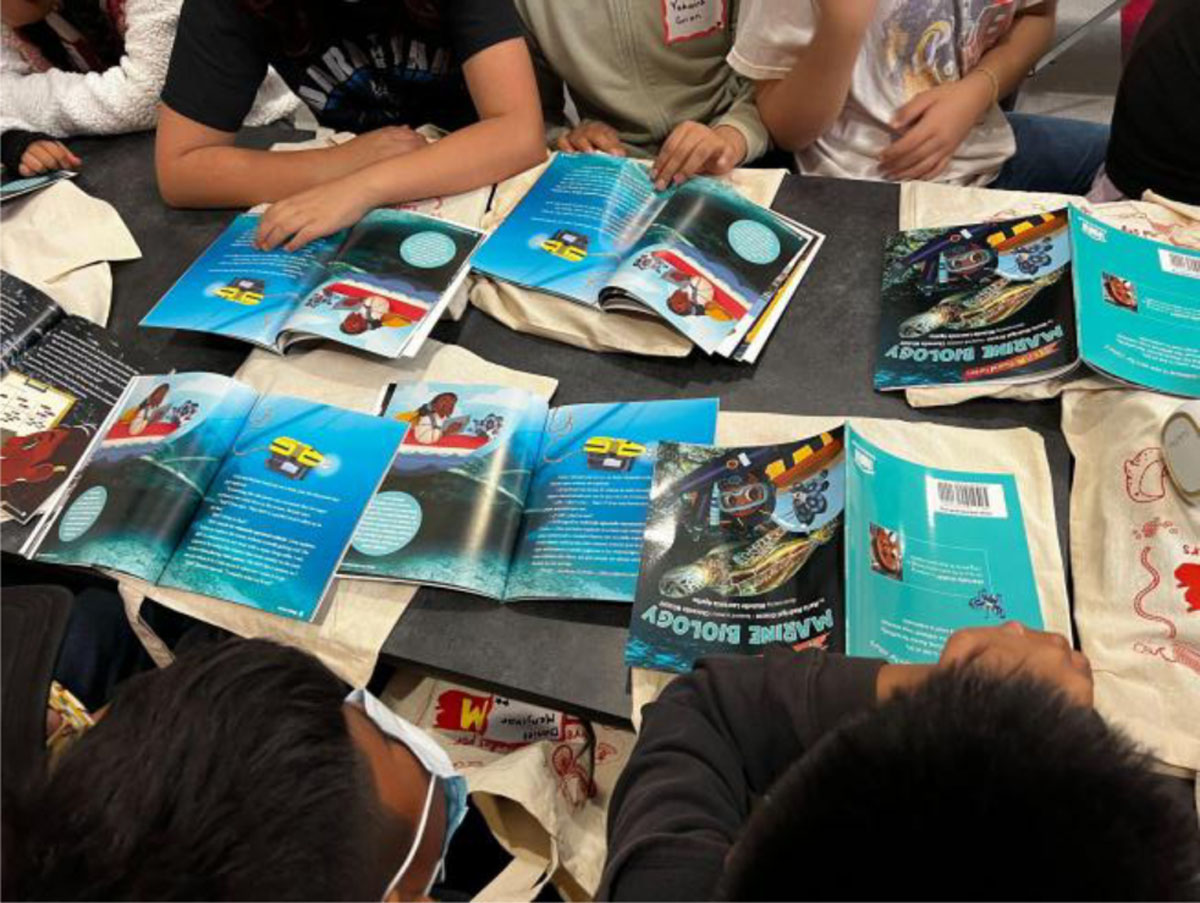 Table covered with open books as students read the spread dedicated to remote operated vehicles, photo taken by Dieuwertje Kast, permission to be reproduced