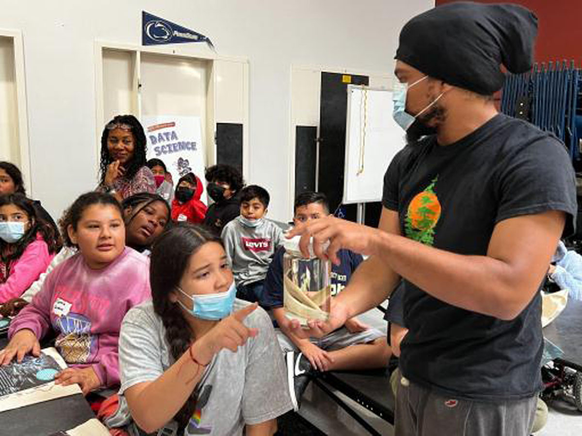 Justin Gaffney, a PhD student in marine environmental biology, showcases grunion to local elementary students during a book reading, photo taken by Dieuwertje Kast, permission to be reproduced