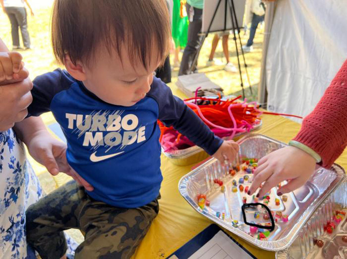 Grayson Fung places a pipe cleaner quadrat in a habitat filled with tiny eraser animals during an educational program. Photo by Dieuwertje Kast. Permission to be reproduced