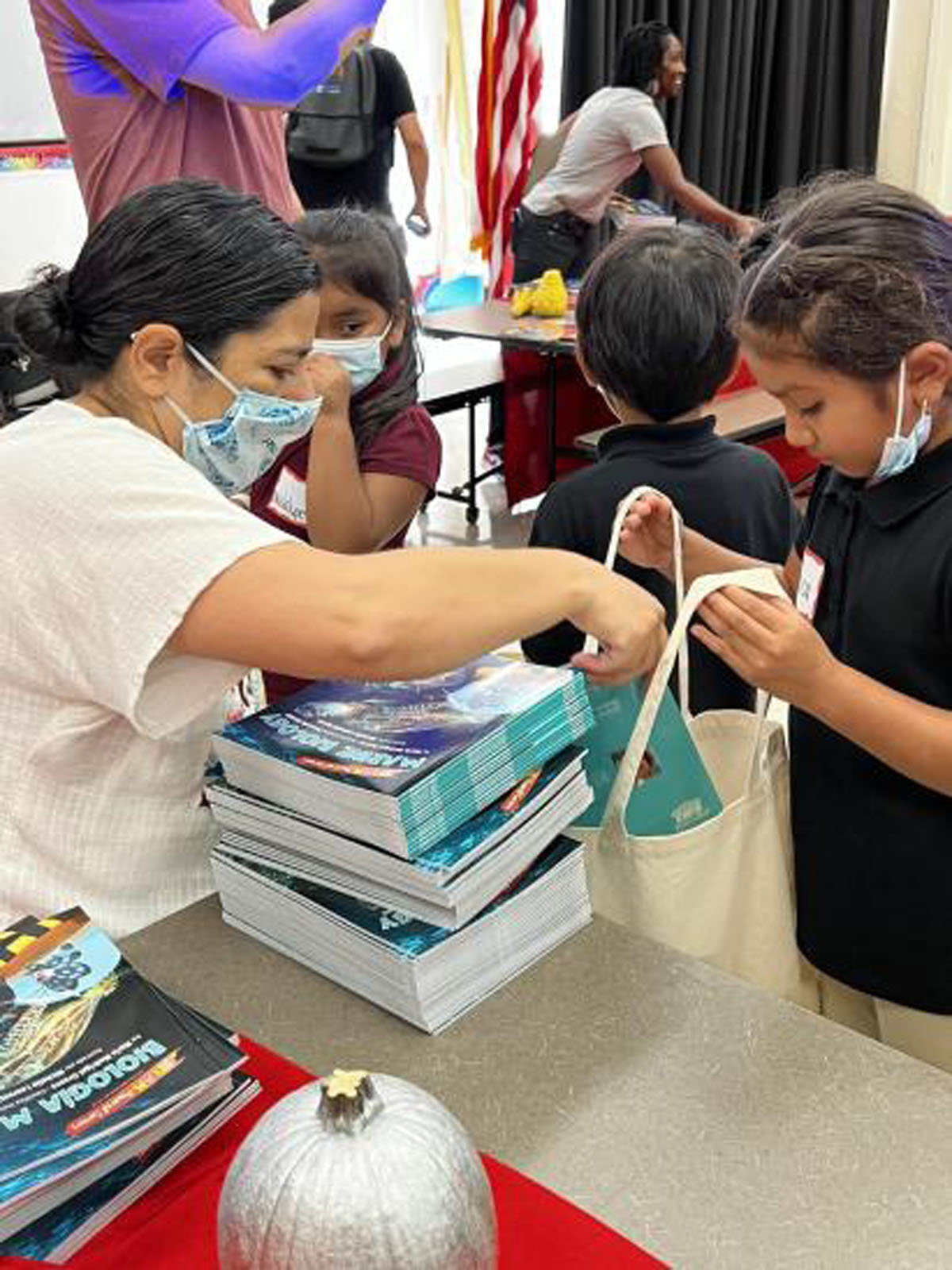 Maria placing book into student’s tote bag at a JEP book assembly, photo by: Dieuwertje Kast, permission to be reproduced