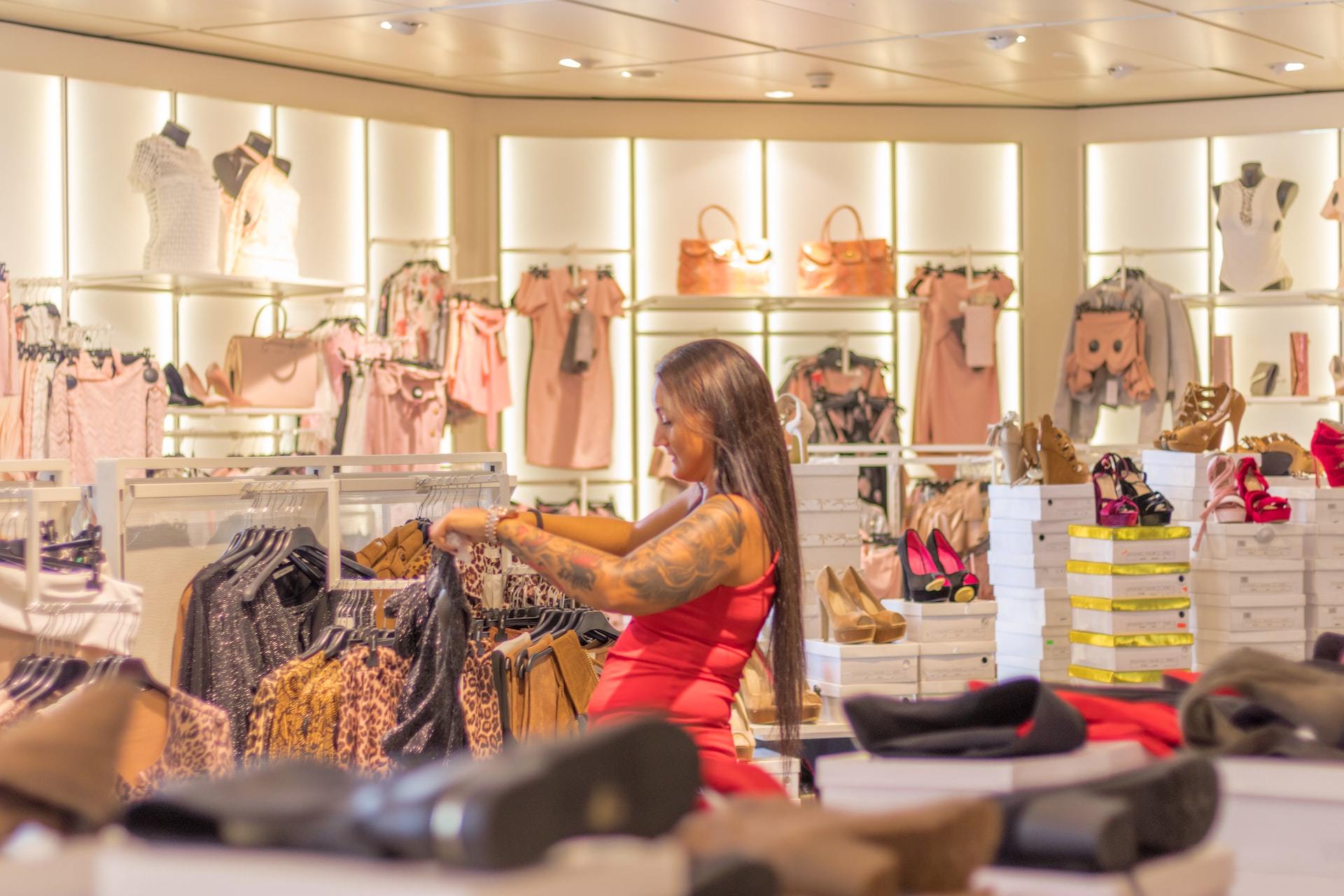 A woman attending to racks of clothing at a clothing store.