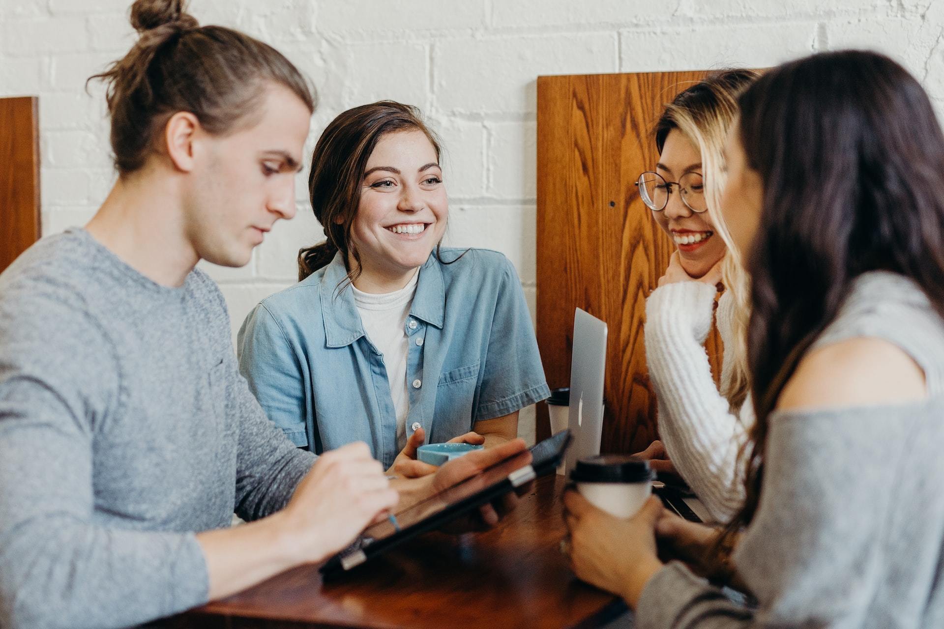 Four employees huddled around a table picking from a tablet.