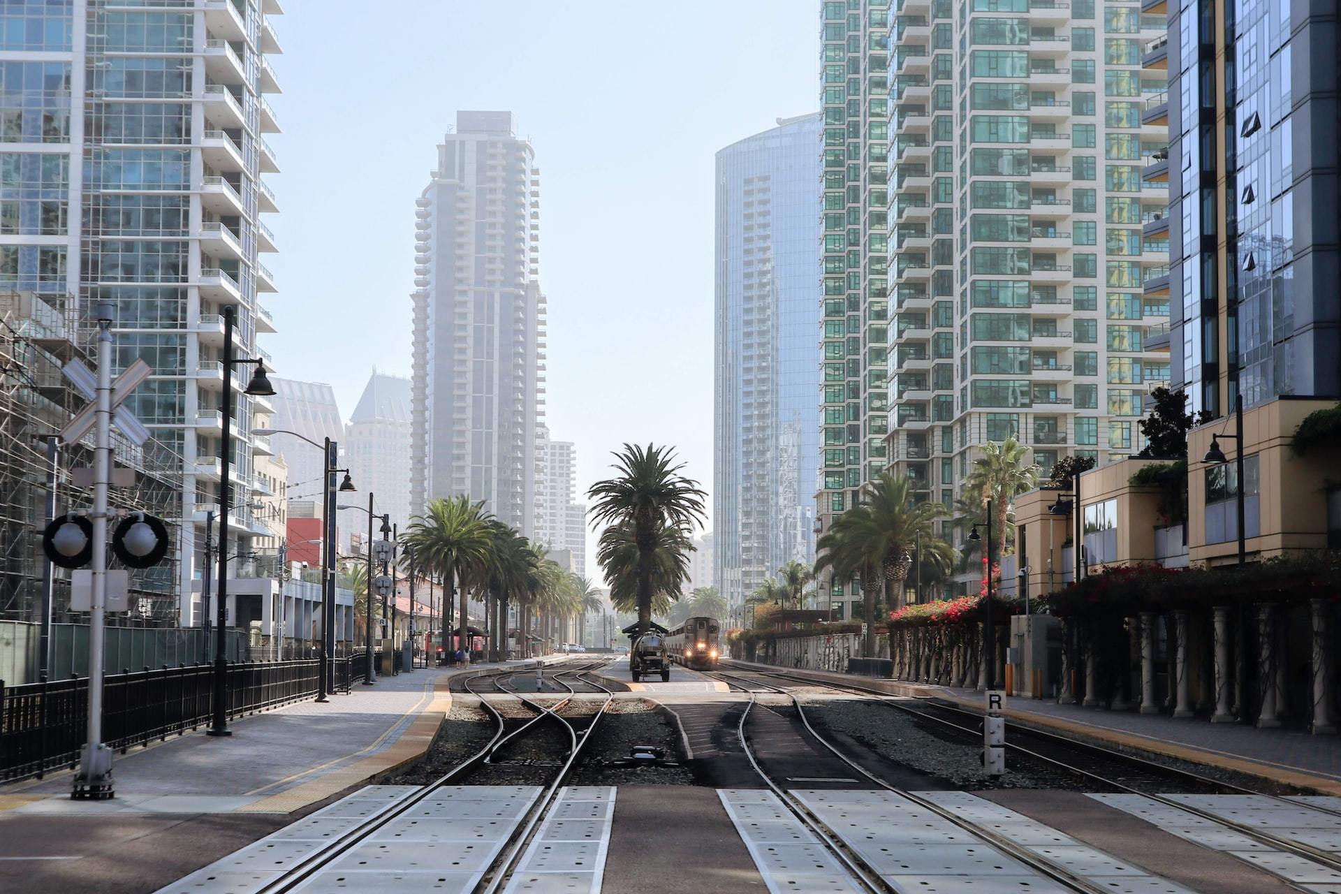 Train tracks and palm trees in between skyscrapers in San Diego.
