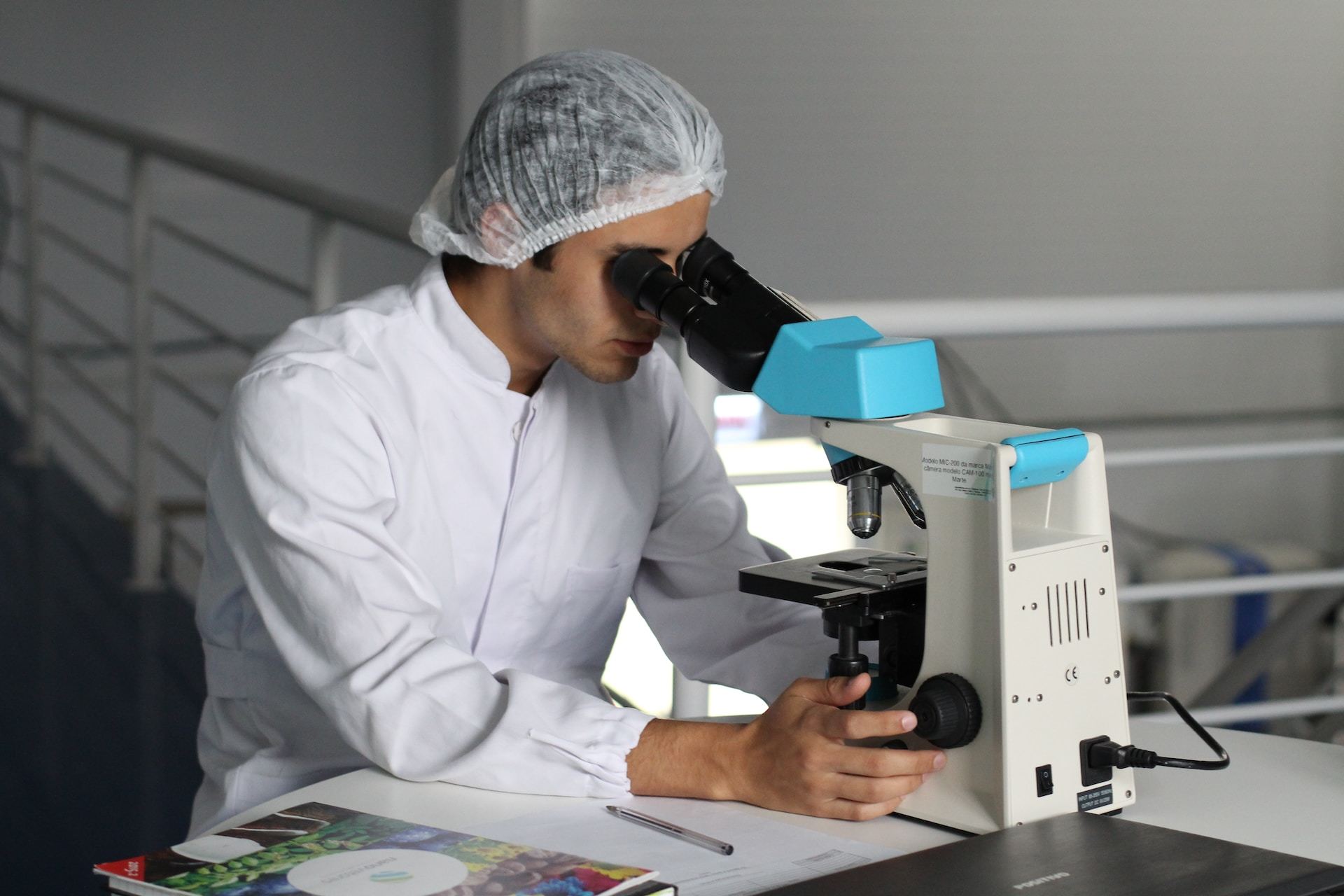 Man sitting behind a microscope in a laboratory setting.