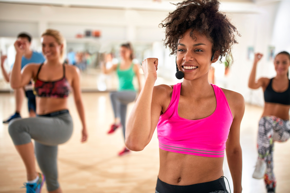 Female instructor with headset in fitness class exercising with group.