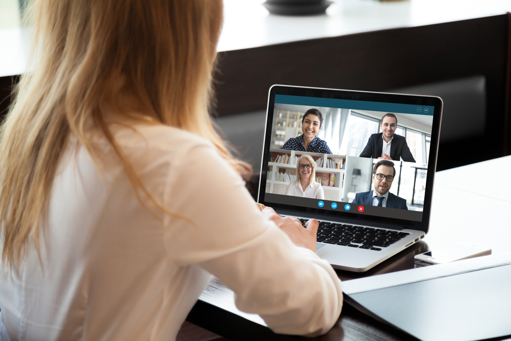 Back view of businesswoman speak using Webcam conference on laptop with diverse colleagues.