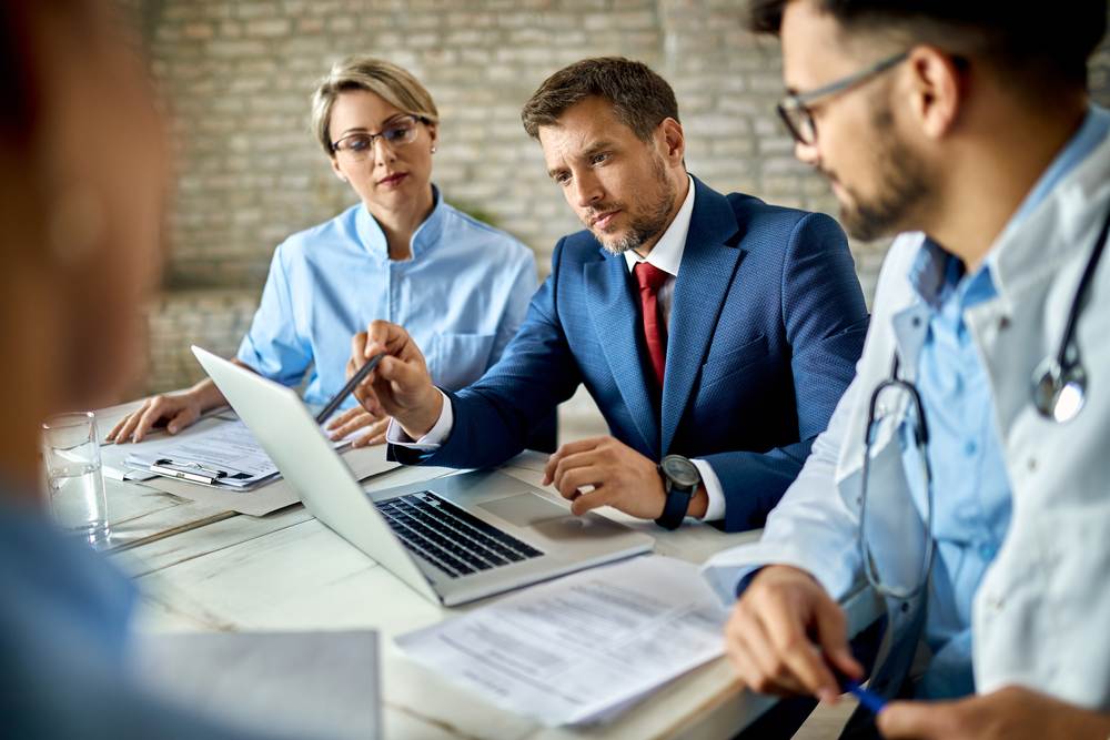 Businessman and group of doctors working on a computer during a meeting..