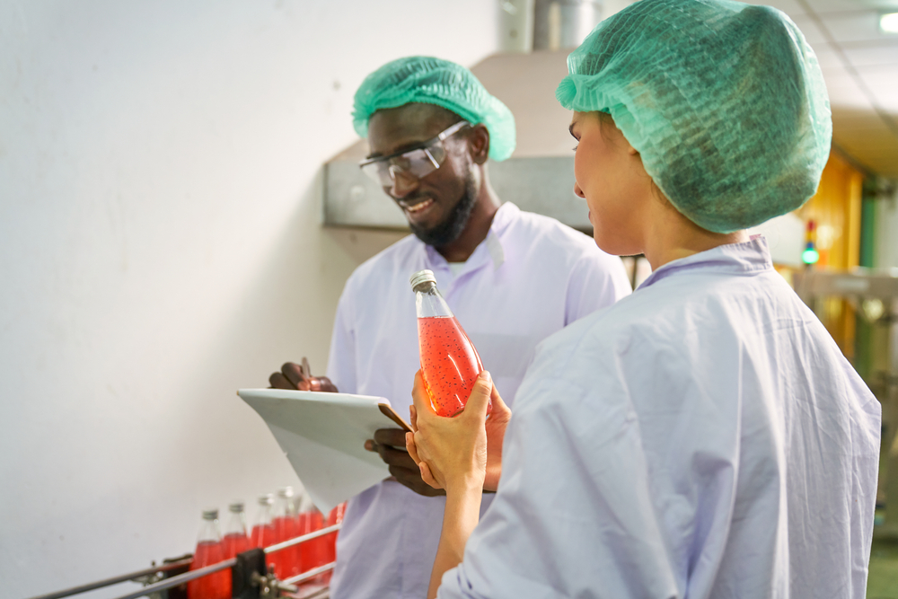 Food scientists check the quality of red juice on an assembly line.