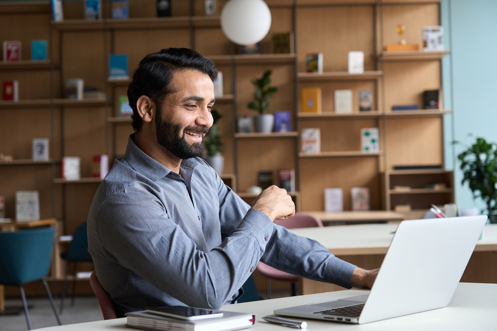 Happy young Indian businessman smiling while having a video conference call.