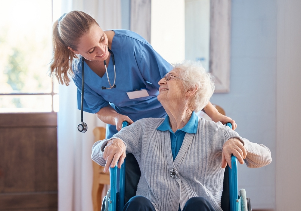 Nurse and elderly woman with a disability in a wheelchair in medical nursing facility.