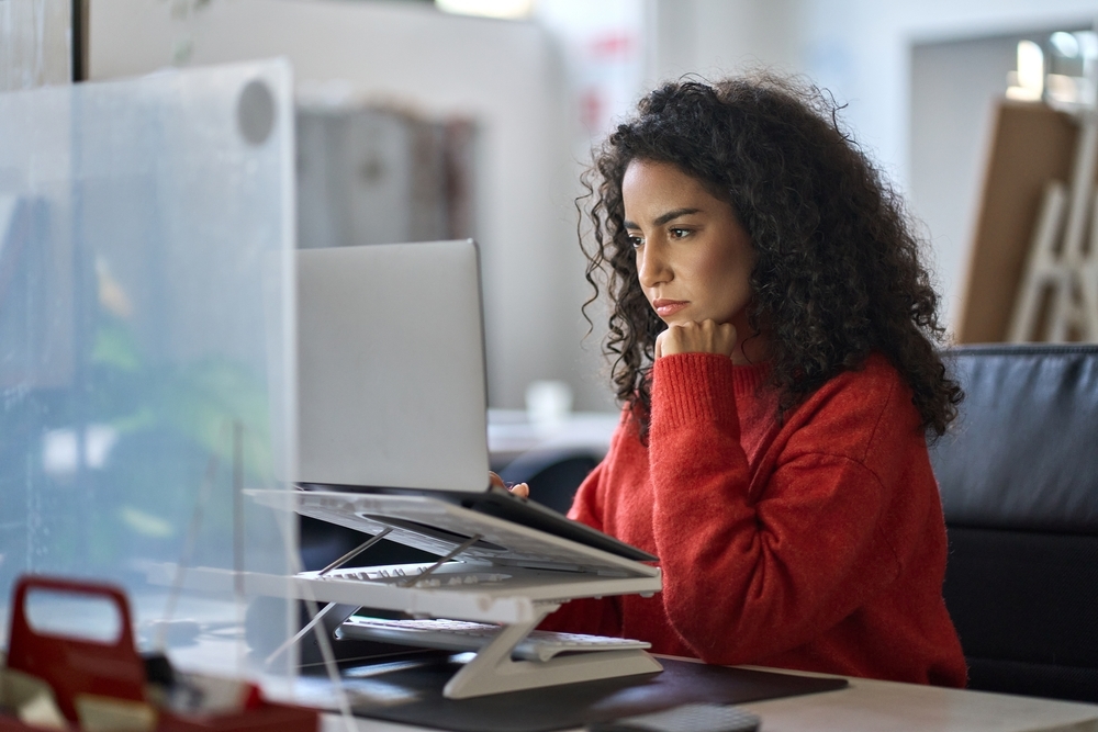 Young latin professional sitting at her desk staring at a computer.