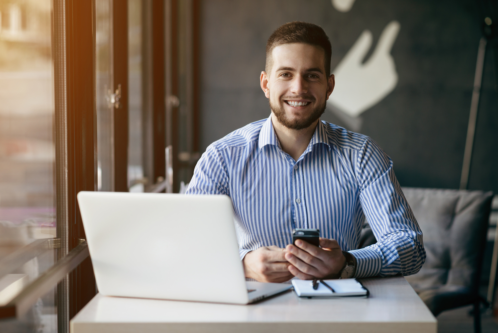 Smiling young professional working on a laptop.