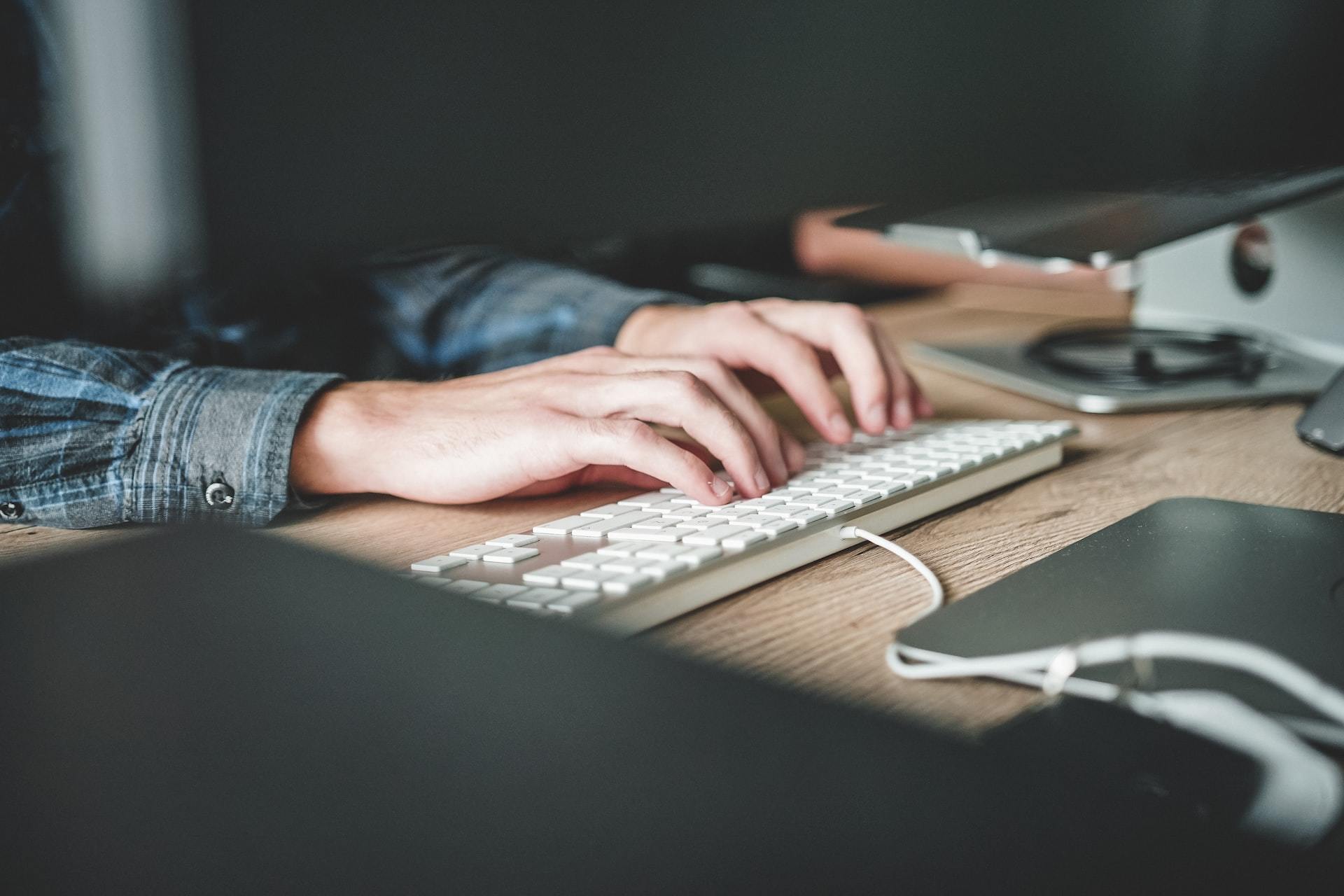 A person's hands typing on a laptop computer.