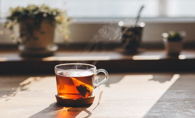 glass cup of tea on a wooden table near the window