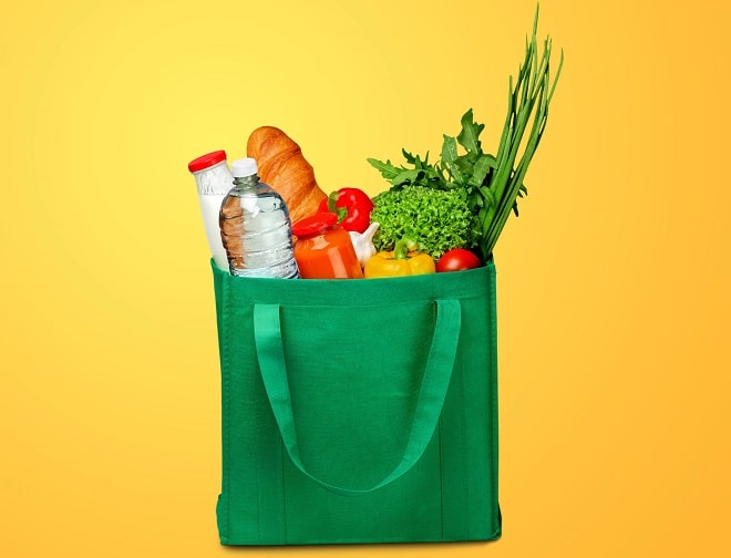 Bag full of groceries on wooden desk with pastel background