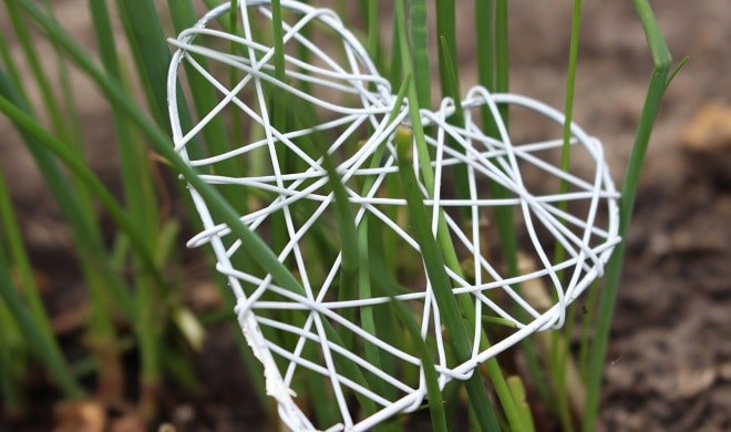 charity community heart made with white wire sitting in grass outdoors