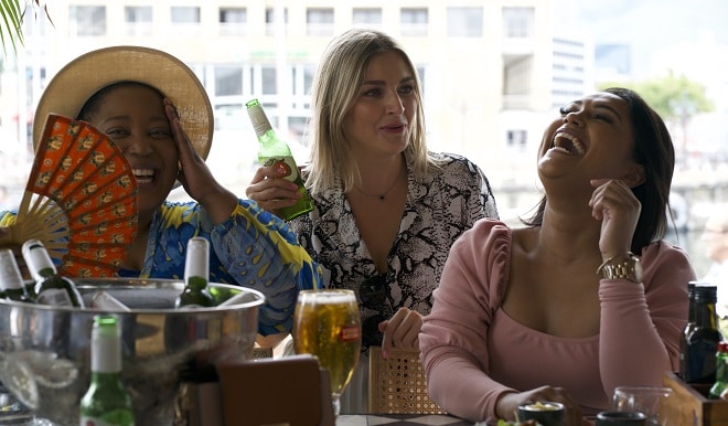 three ladies sitting at a bar enjoying stella artois beer and laughing