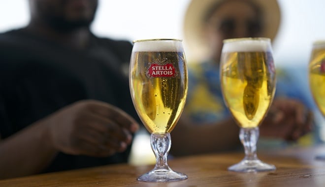 stella artois beer in glasses on a wooden table with two men in the background out of focus