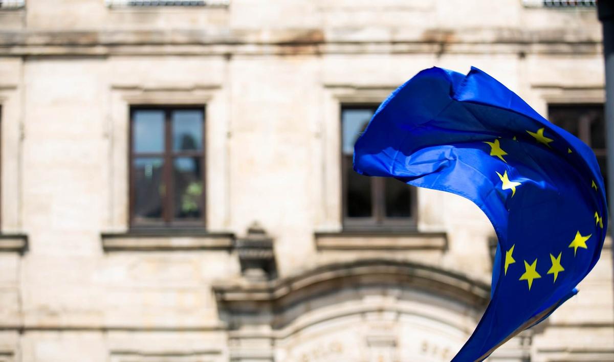 Flag of the EU, where the unlimited paid time off policy is much less common, waving in front of a building