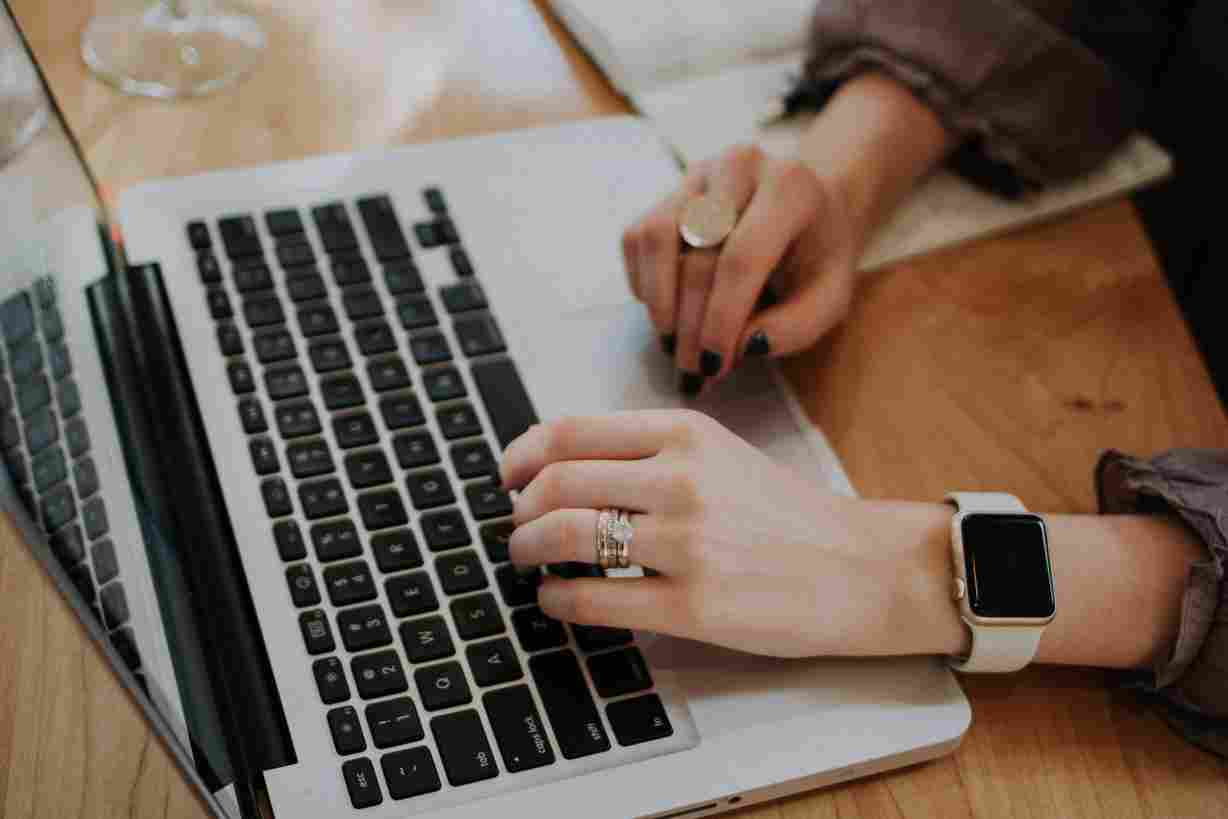 Woman sitting at a desk typing on her laptop, representing the concept of proper email netiquette