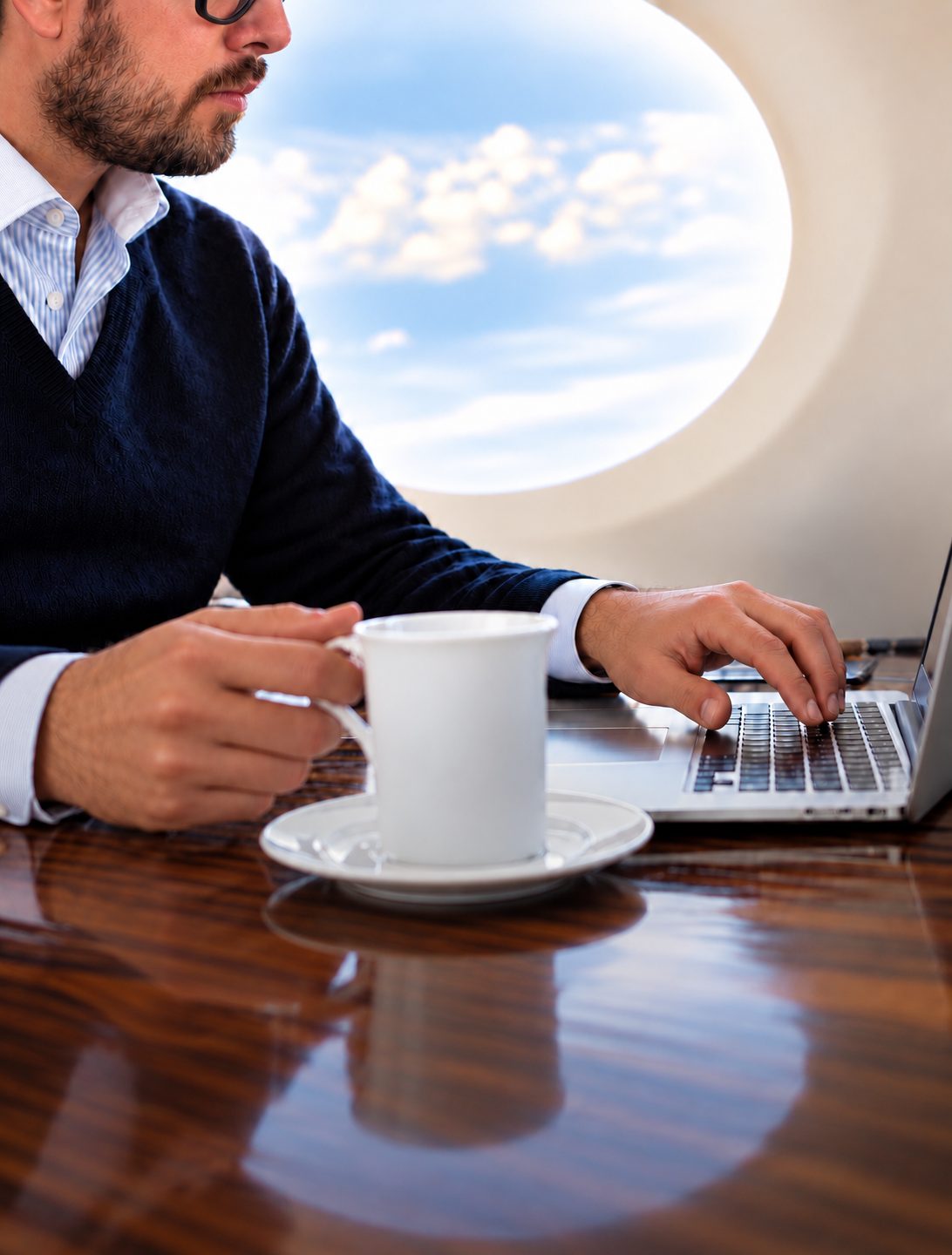 Coffee and a laptop beside the window of a private jet cabin