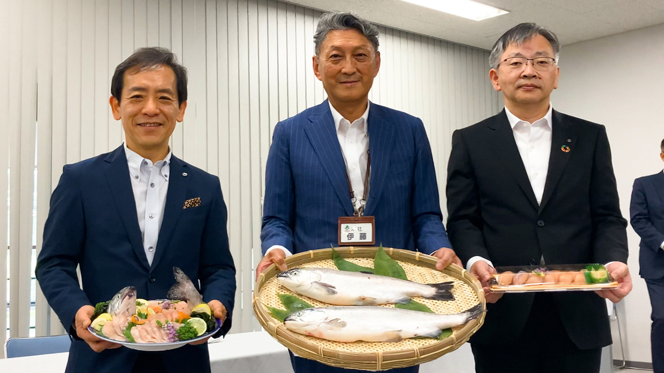 Naoki Shibutani, president and CEO of NTT East Japan (left), Nobuhiro Ito, president and CEO of Fukushima City’s Ichii supermarket chain (center), and Hiroyuki Hirano, president of Okayama University of Science, hold sockeye salmon, sushi and sashimi. &nbsp; &nbsp; Source: NTT East