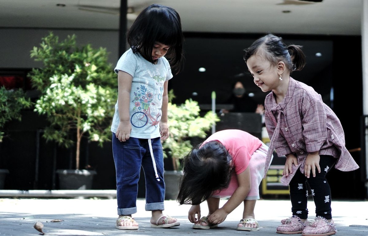 Three young children playing together outdoors