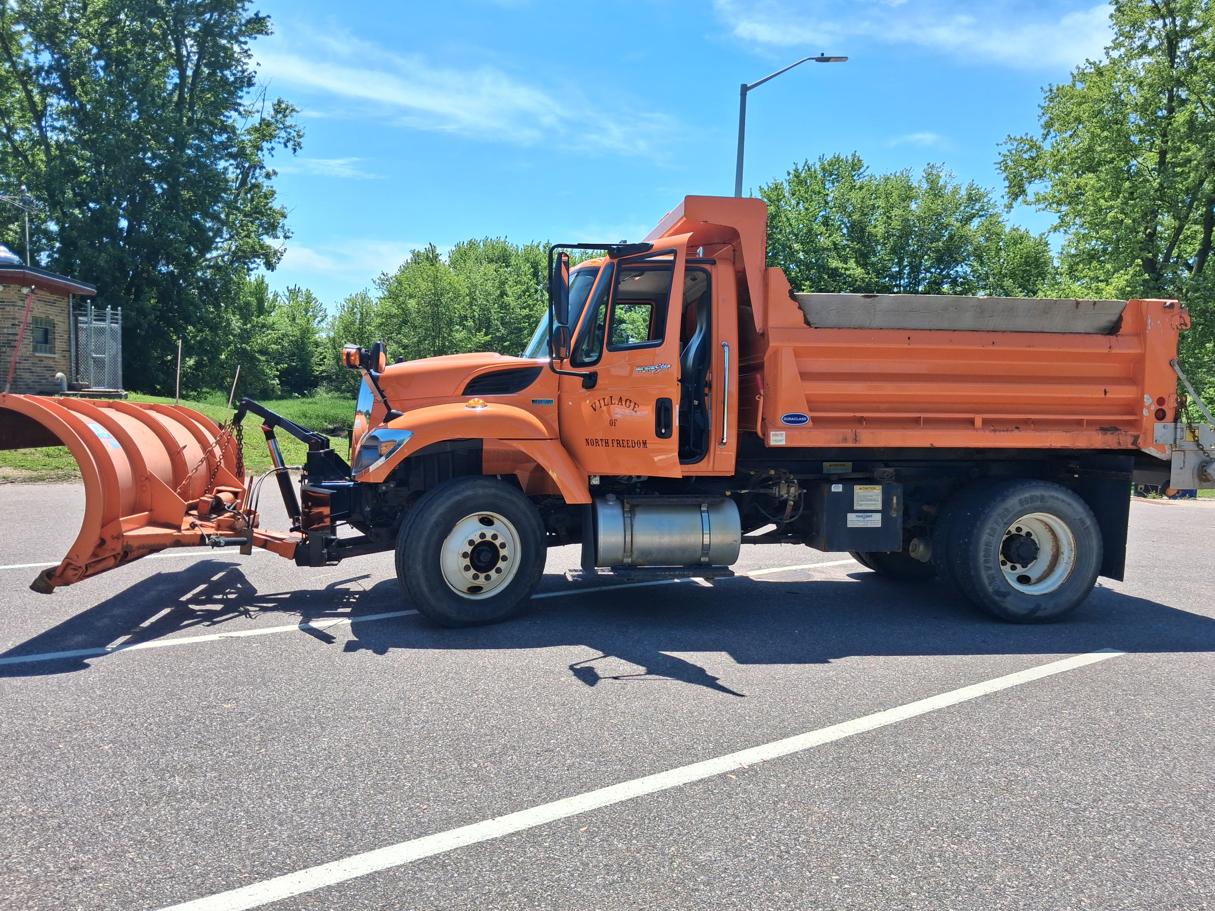 Driver's Side View of Orange Dump Truck with Plow
