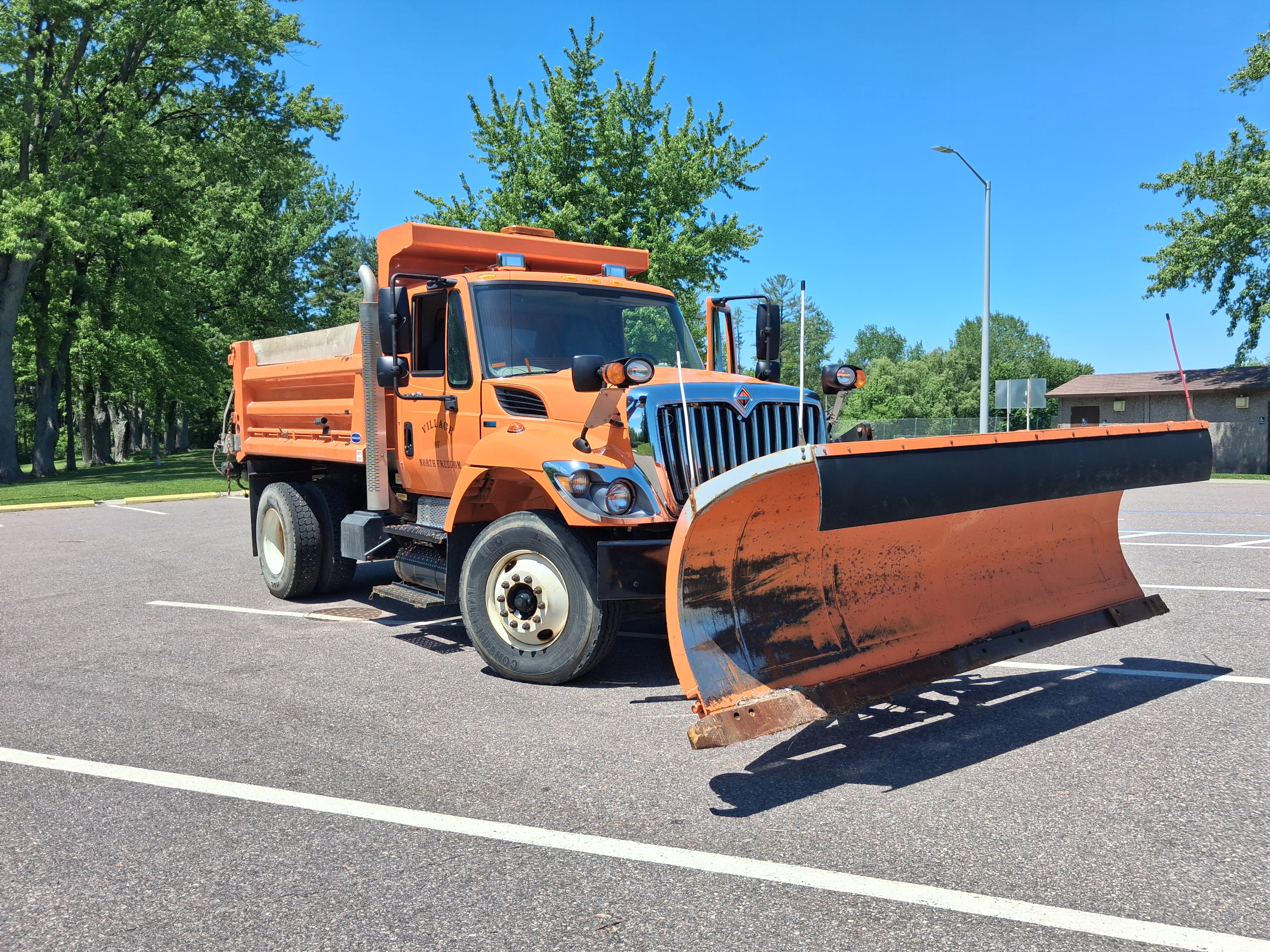 Passenger Side Front View of Orange Dump Truck with Plow
