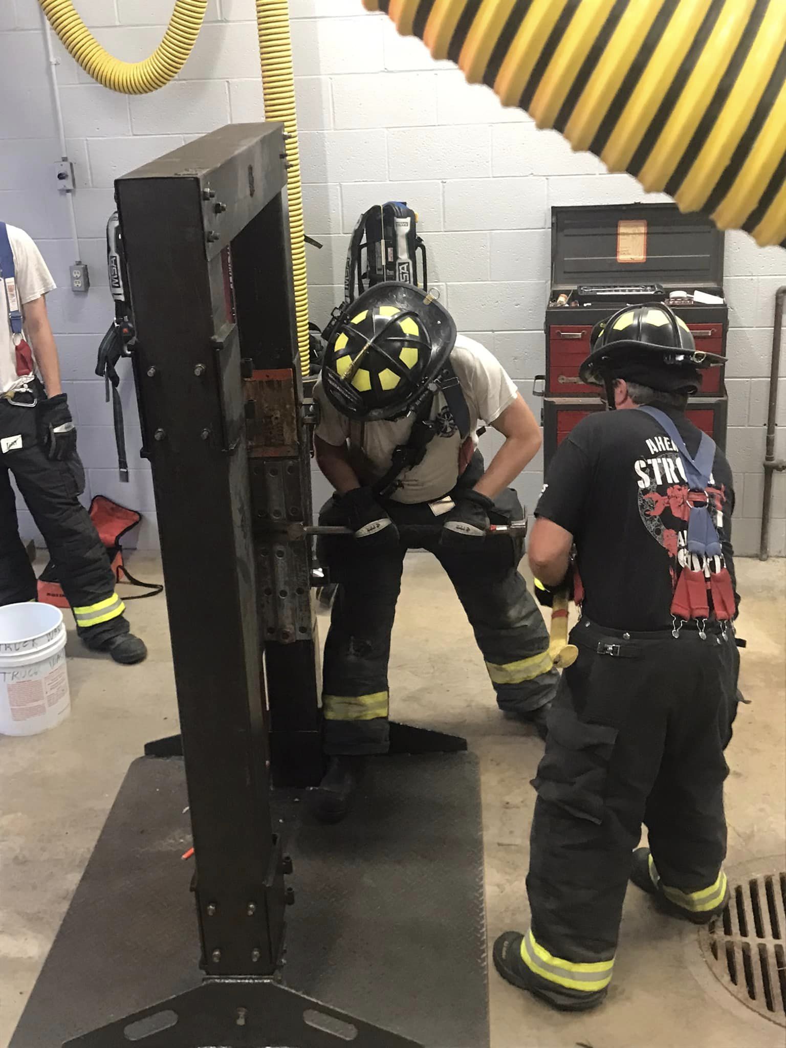 Firefighters applying tools on training door