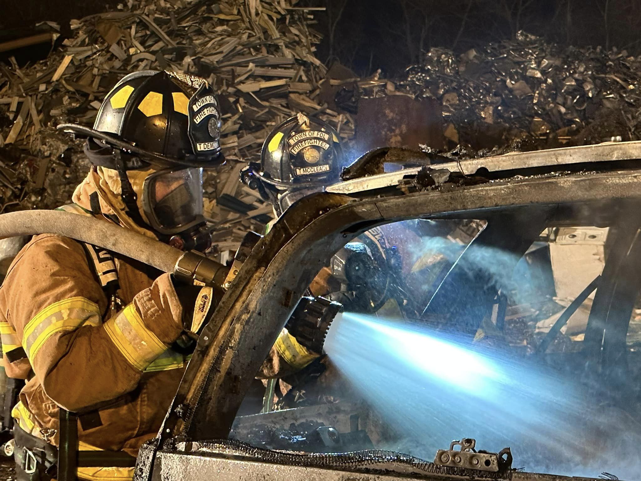 Firefighter spraying water on car fire